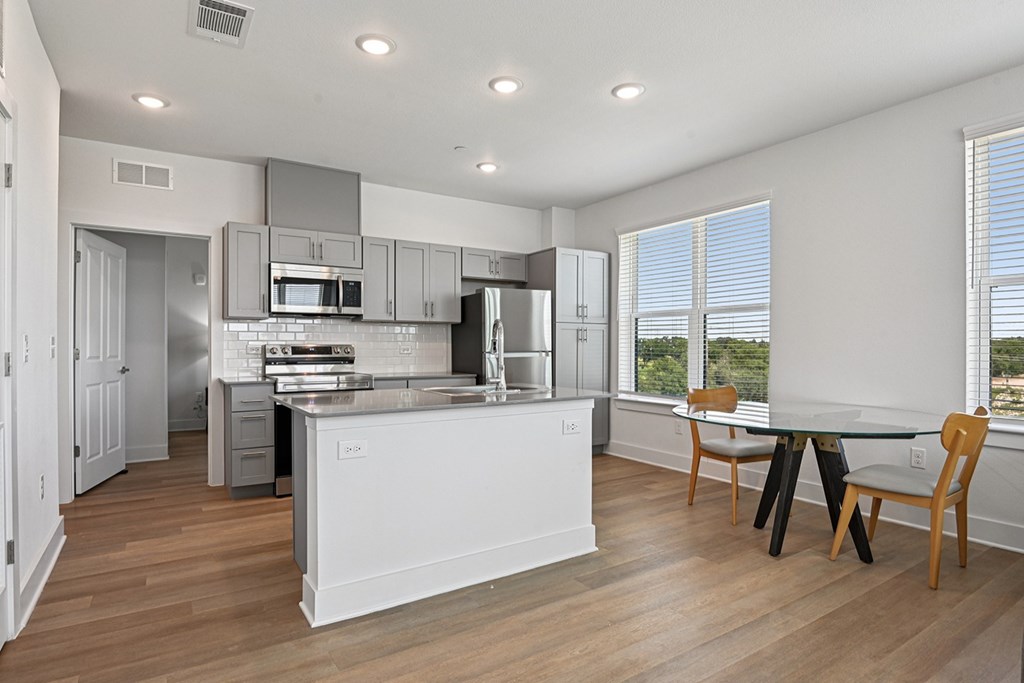 A modern kitchen with white cabinets and a wooden floor.