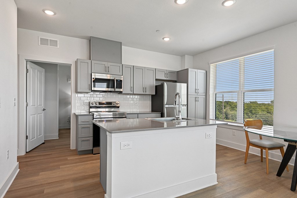 A modern kitchen with a large island and stainless steel appliances.