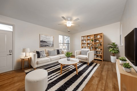 A living room with a white couch, a black and white striped rug, and a wooden bookshelf.