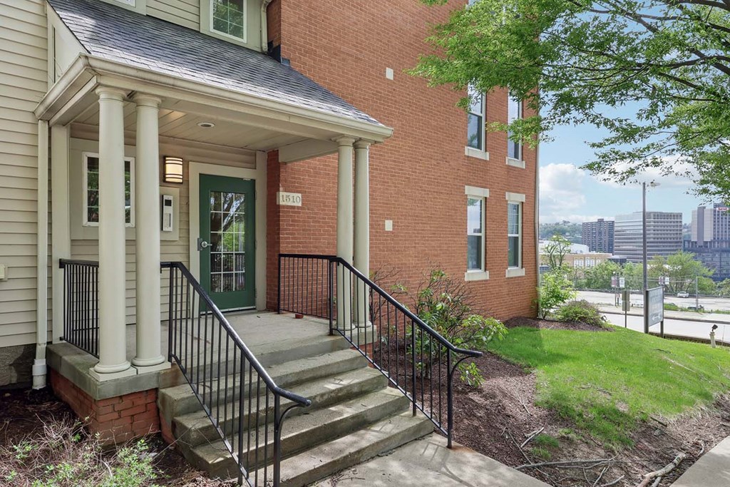 A red brick house with a green door and a black railing.
