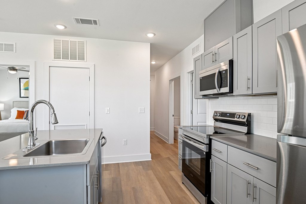 A modern kitchen with stainless steel appliances and wooden floors.