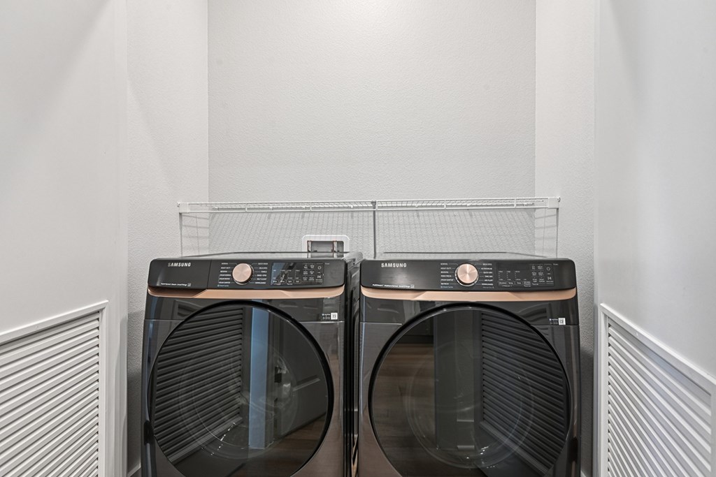Two Samsung front loading washing machines in a laundry room.