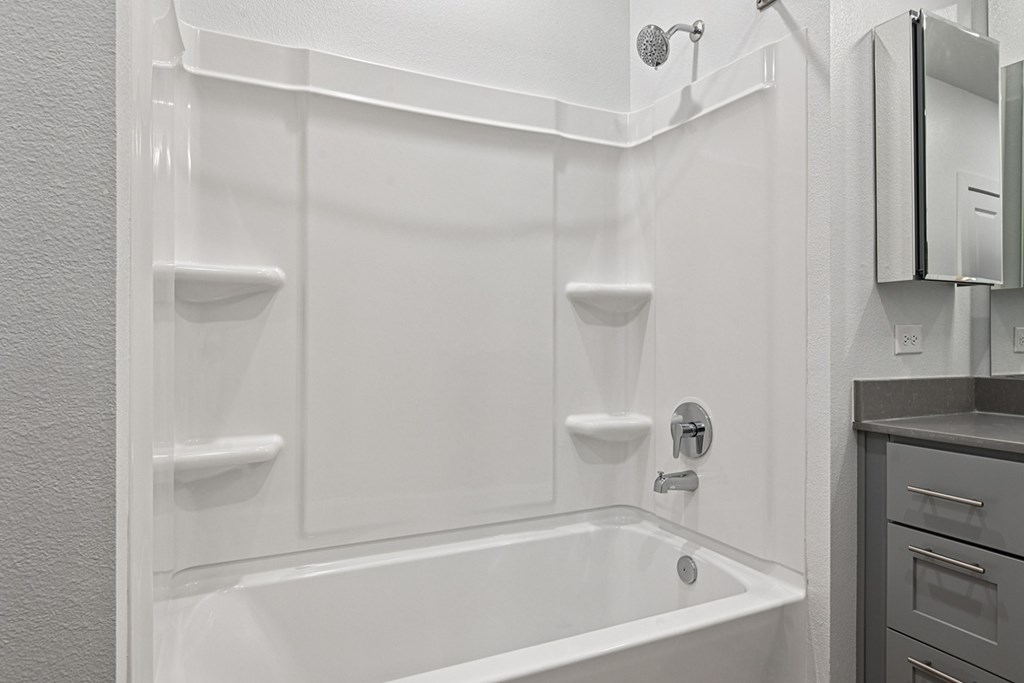 A white bathroom with a tub and a towel rack.