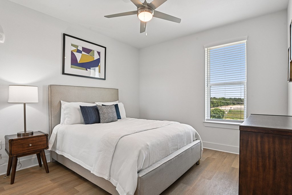 A bedroom with a large bed and a ceiling fan.