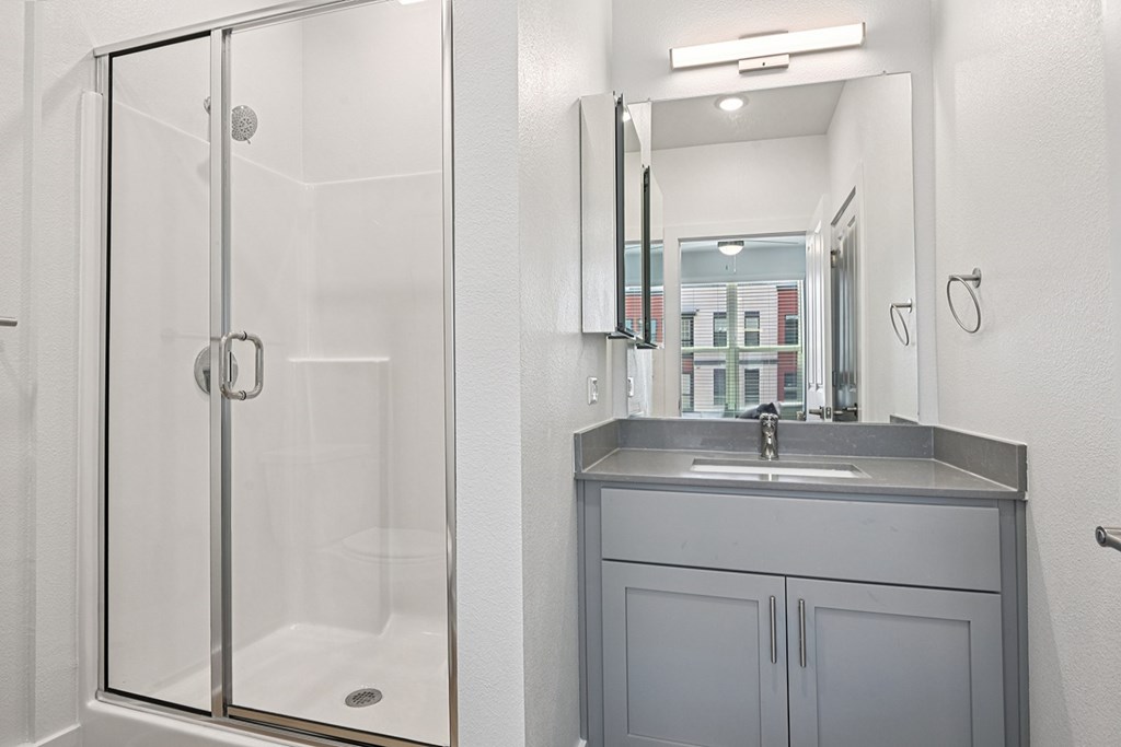A bathroom with a sink, mirror, and shower.
