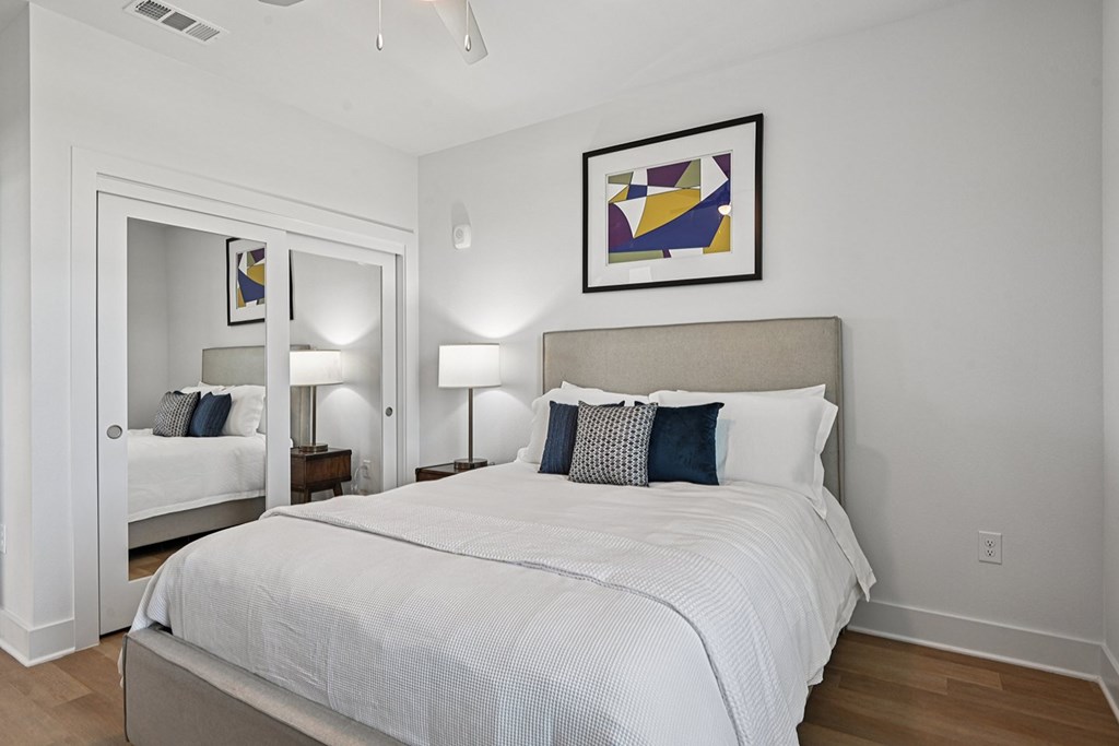 A bedroom with a large bed and a painting on the wall.