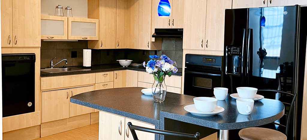 a kitchen with black appliances and a counter with blue countertops and a vase
