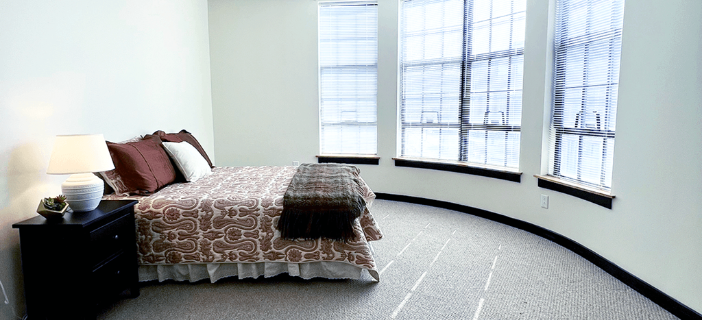 a bedroom with a bed and three large windows