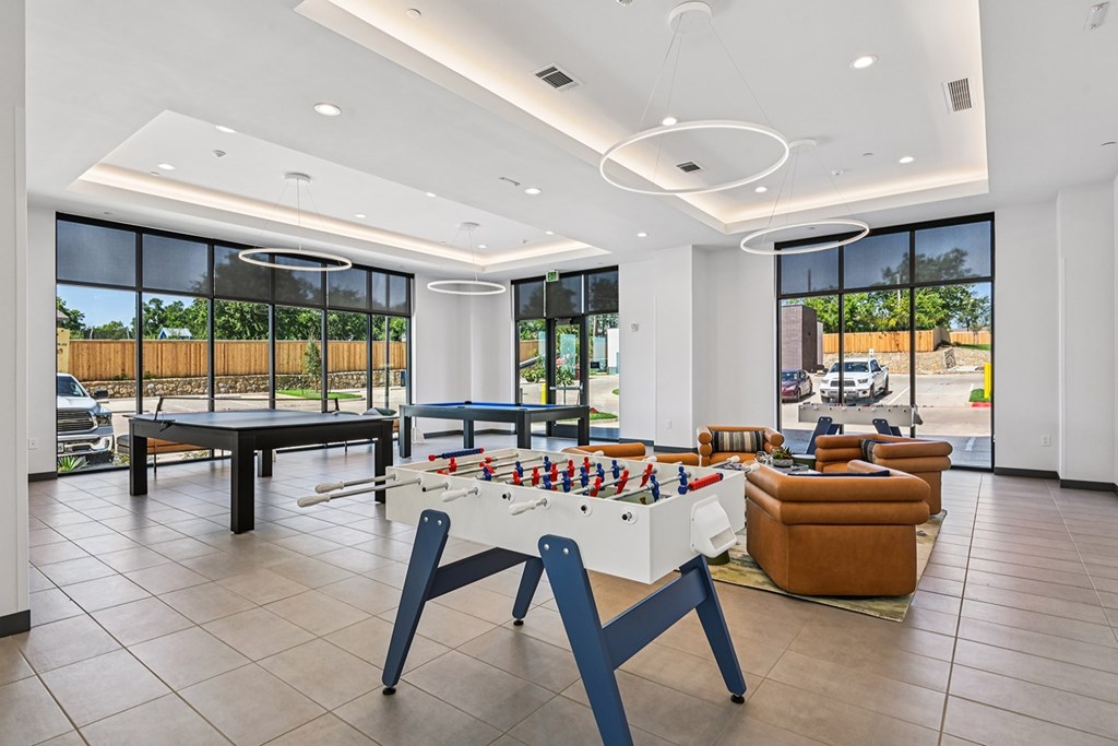 A foosball table is in the middle of a room with a white ceiling and tiled floor.