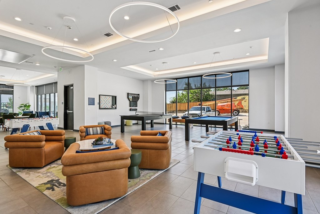 A foosball table is in the middle of a living room with a couch and chairs.