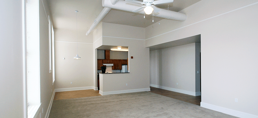 an empty living room with carpet and a ceiling fan