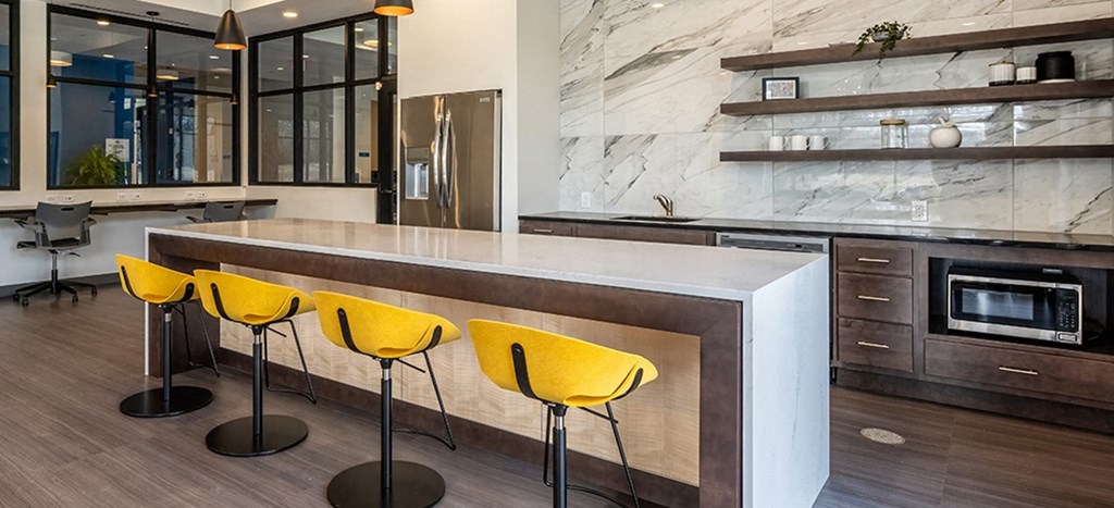 a kitchen with a large counter and yellow chairs