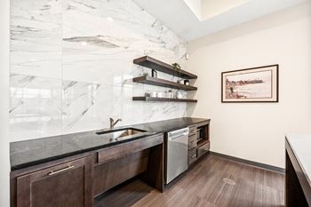 A kitchen with a marble backsplash and dark wood cabinets.