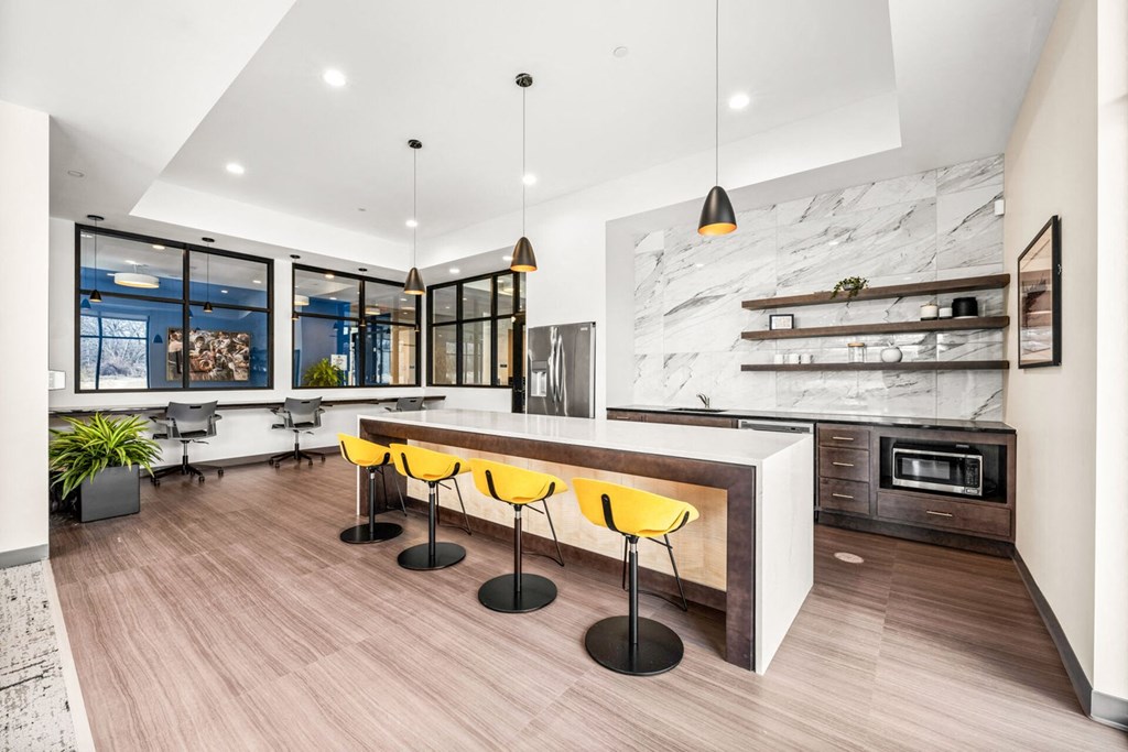 A modern kitchen with a bar area and yellow chairs.