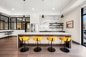 A modern kitchen with a marble backsplash and yellow bar stools.