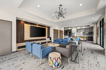 A modern living room with a large flat screen TV, blue chairs, and a wooden coffee table.