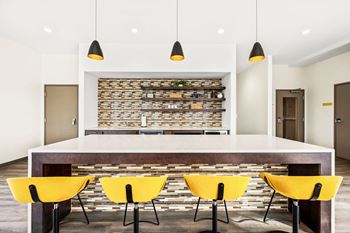 A modern dining room with a stone backdrop and yellow chairs.