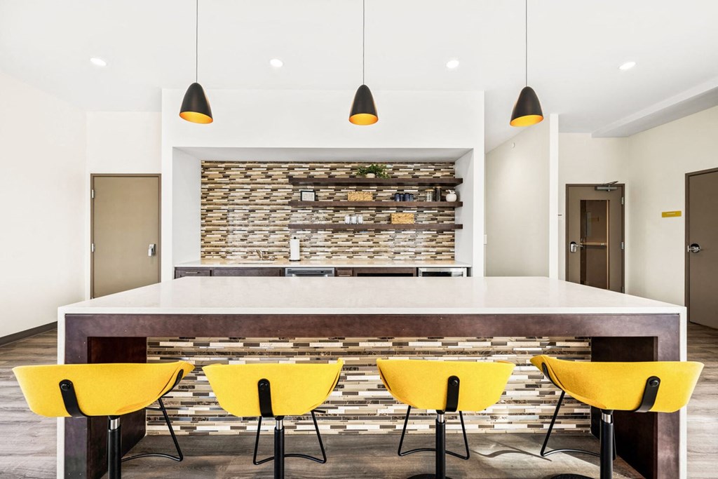 A modern dining room with a stone backdrop and yellow chairs.