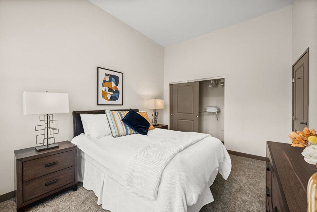 A bedroom with a bed, nightstand, and a painting on the wall.