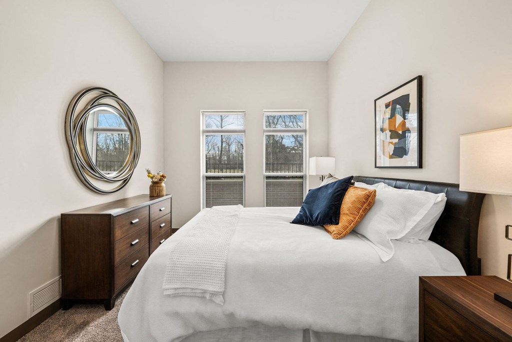A bedroom with a large bed and a round mirror on the wall.