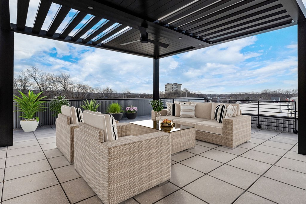 A patio with a wicker sofa and a table with a plant on it.