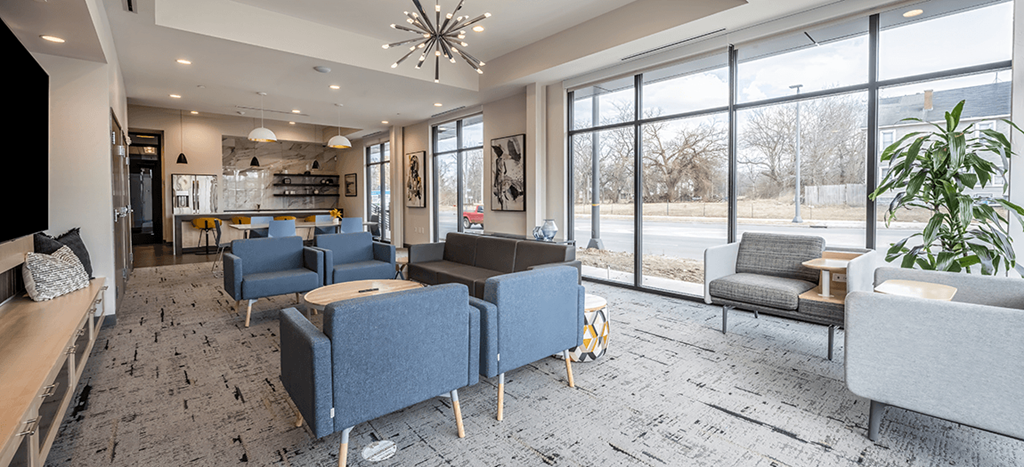 Aura at Innovation apartments clubhouse with blue chairs and tables and large windows