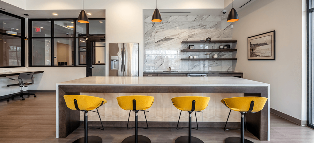 Aura at Innovation clubhouse: a modern kitchen with yellow chairs in front of a counter