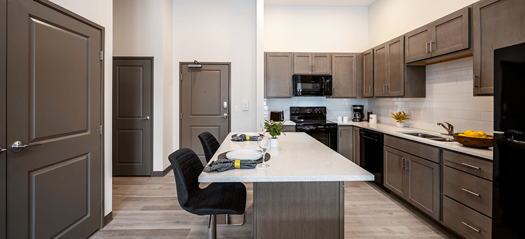 a kitchen with a quartz counter top and a dining room table at Aura at Innovation Square apartments