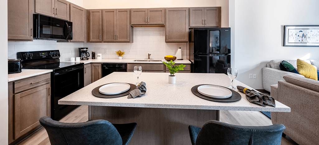 a kitchen and living room with a table with plates on it at Aura at Innovation Square apartments