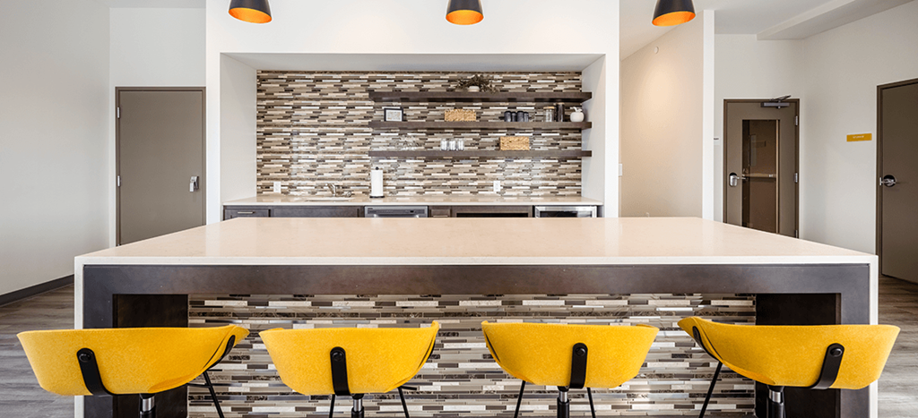 a modern kitchen with yellow chairs in front of a counter
