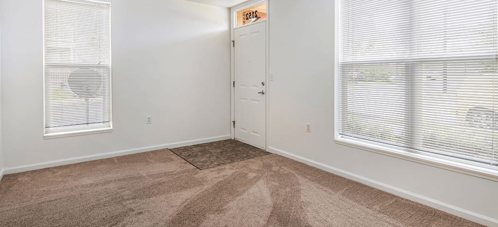 Living room with carpet and two windows and a door