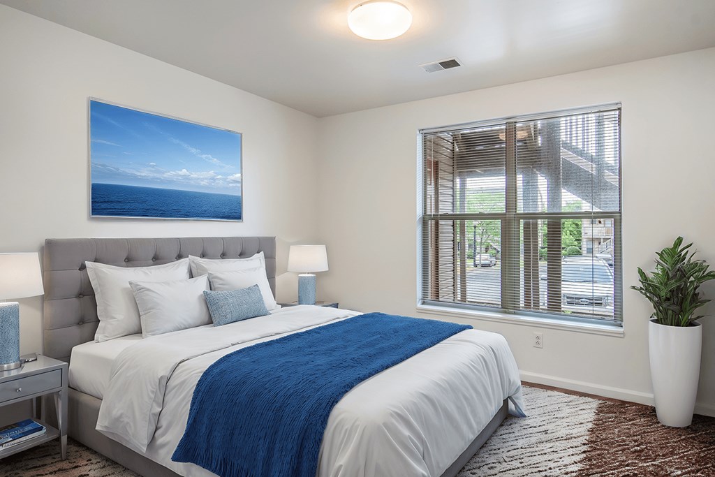 A bedroom with a large bed and a picture of the sea on the wall.
