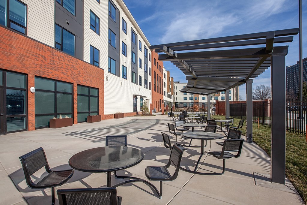 an outdoor patio area with tables and chairs and a building in the background