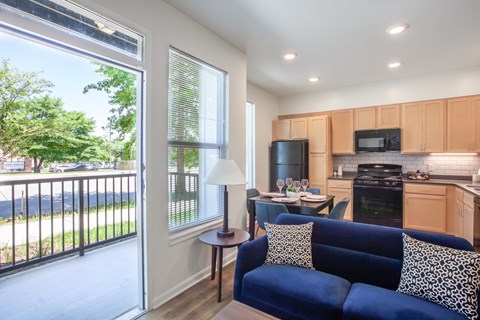 A blue couch with a leopard print pillow sits in a kitchen with wooden cabinets.