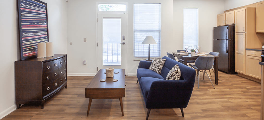 a living room with a couch and a dining table and a refrigerator surrounded by cabinets