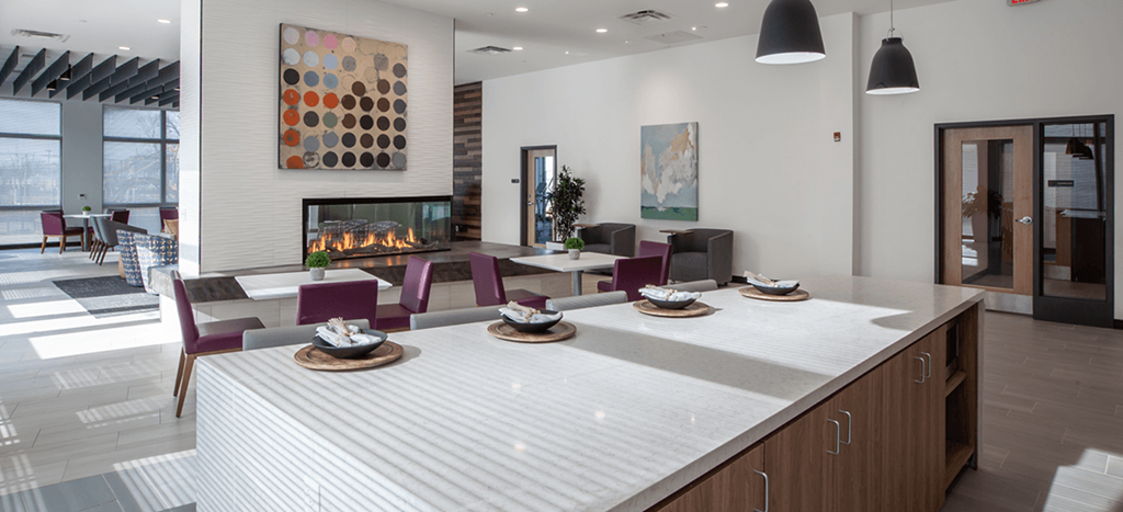 a large clubhouse kitchen and dining area with a fireplace and a table and chairs