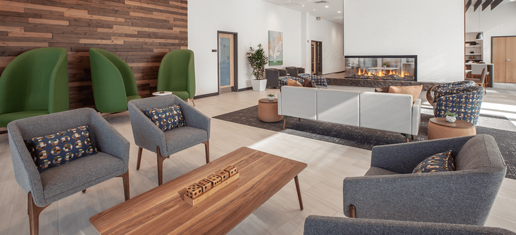 a clubhouse lounge with chairs and a table and a fireplace