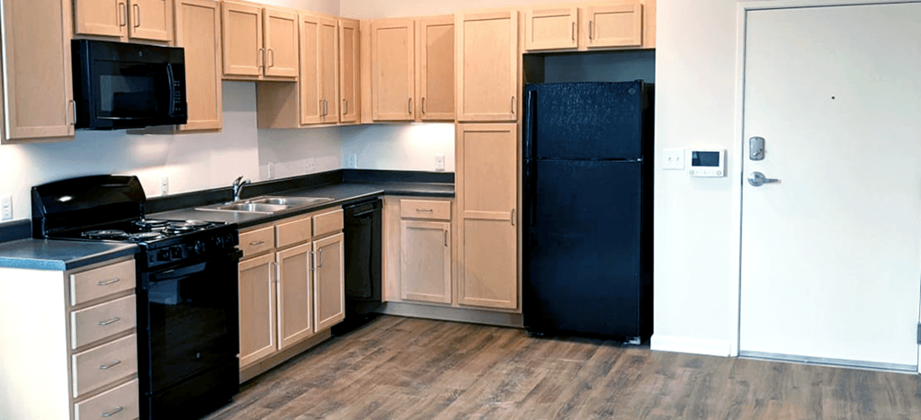 an empty kitchen with black appliances and white cabinets