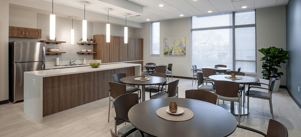 Beecher Senior Apartments community room with tables and chairs and a kitchen