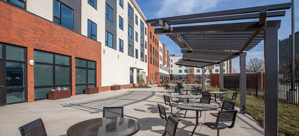a patio with tables and chairs outside of Beecher Senior Apartments