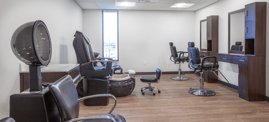 a salon room with a variety of chairs and a mirror at Beecher Senior Apartments