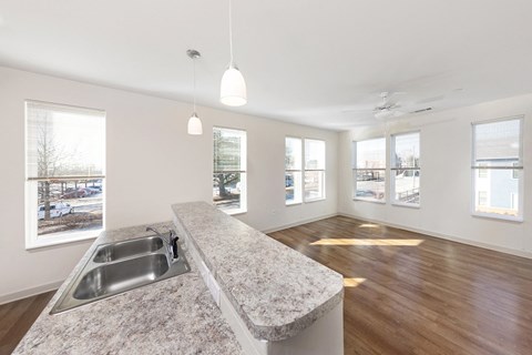 an empty living room with a kitchen counter top and a sink