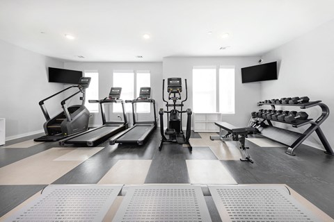 a gym with treadmills and other exercise equipment in a room with windows