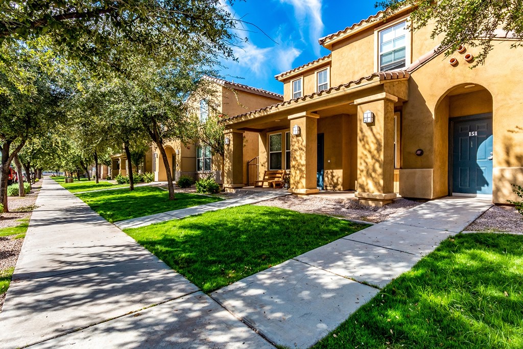 A row of houses with green lawns and trees.