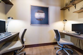 Two chairs and two desks in a room with a painting on the wall.