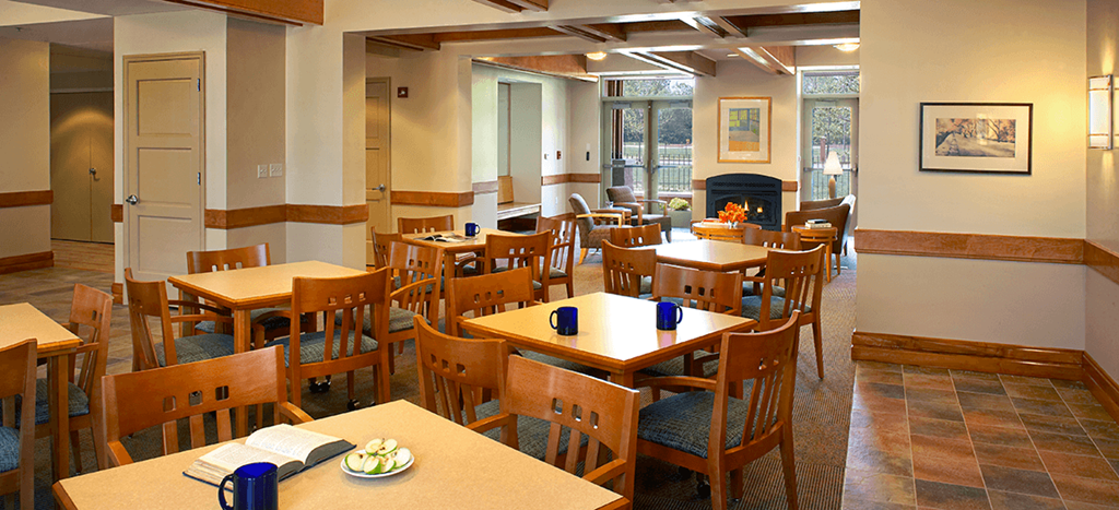 a community room at Cahill House apartments with tables and chairs and a fireplace