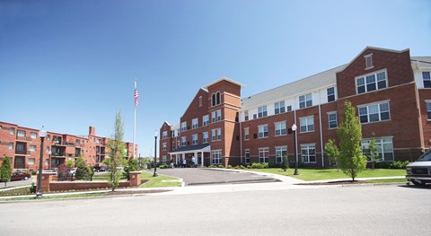 a large brick building with an flag in front of it at Cambridge Senior Living