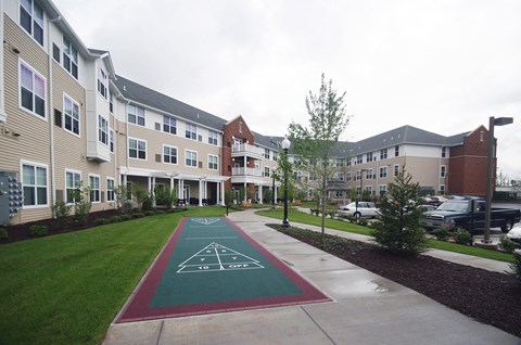 a path leading to an apartment building with a green sidewalk and a green lawn with