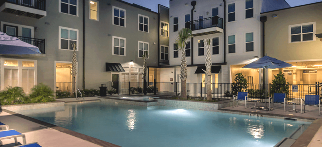 a swimming pool in front of an apartment building at night