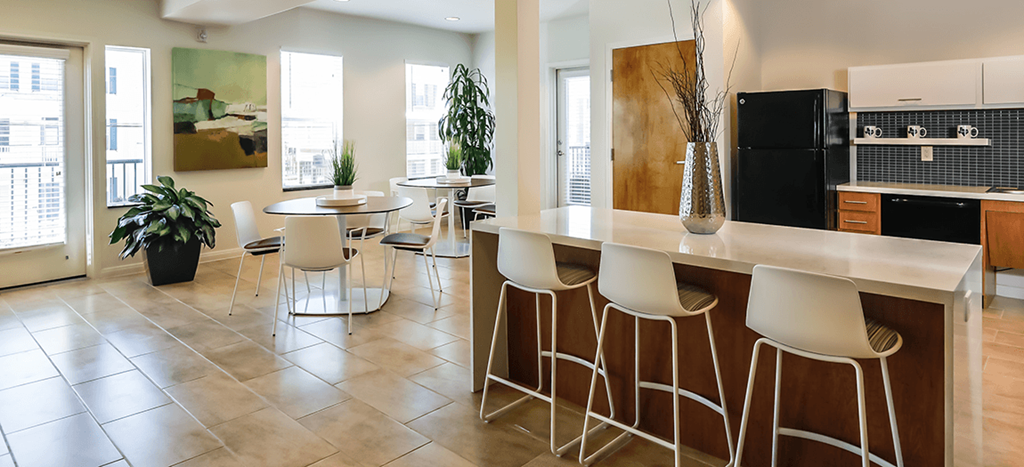 Cedars at Carver Park clubhouse kitchen with a bar and stools and a table with chairs